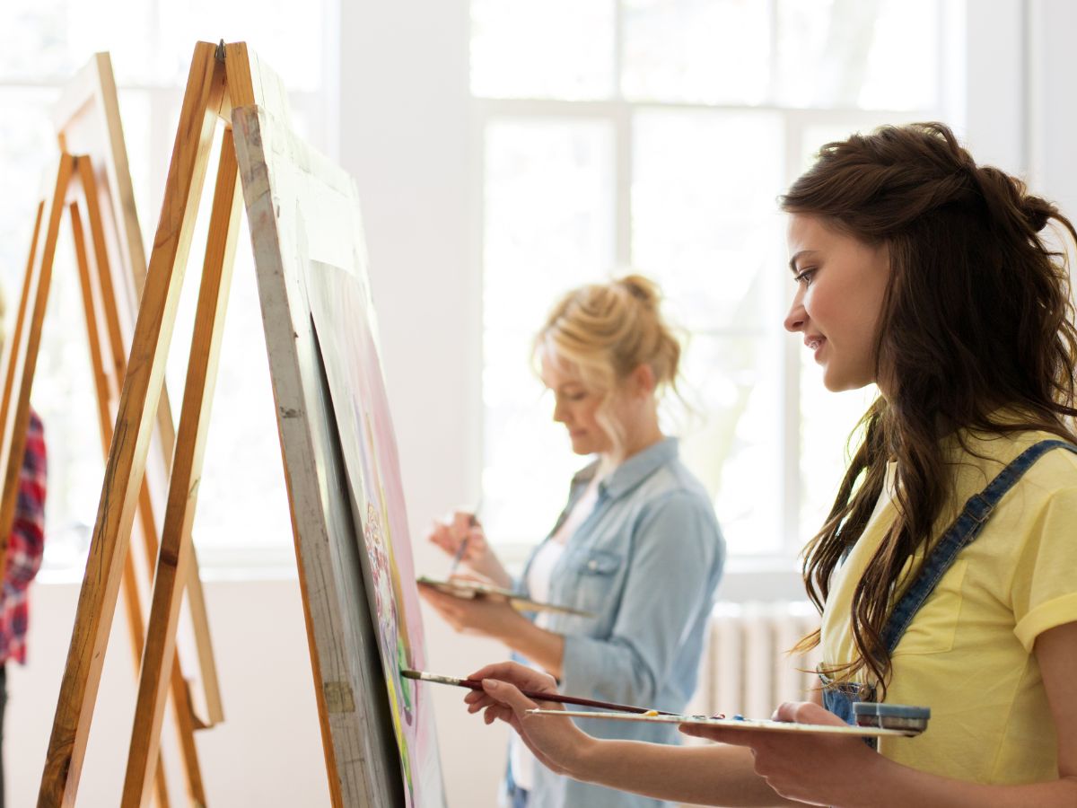 two woman painters in front of canvas