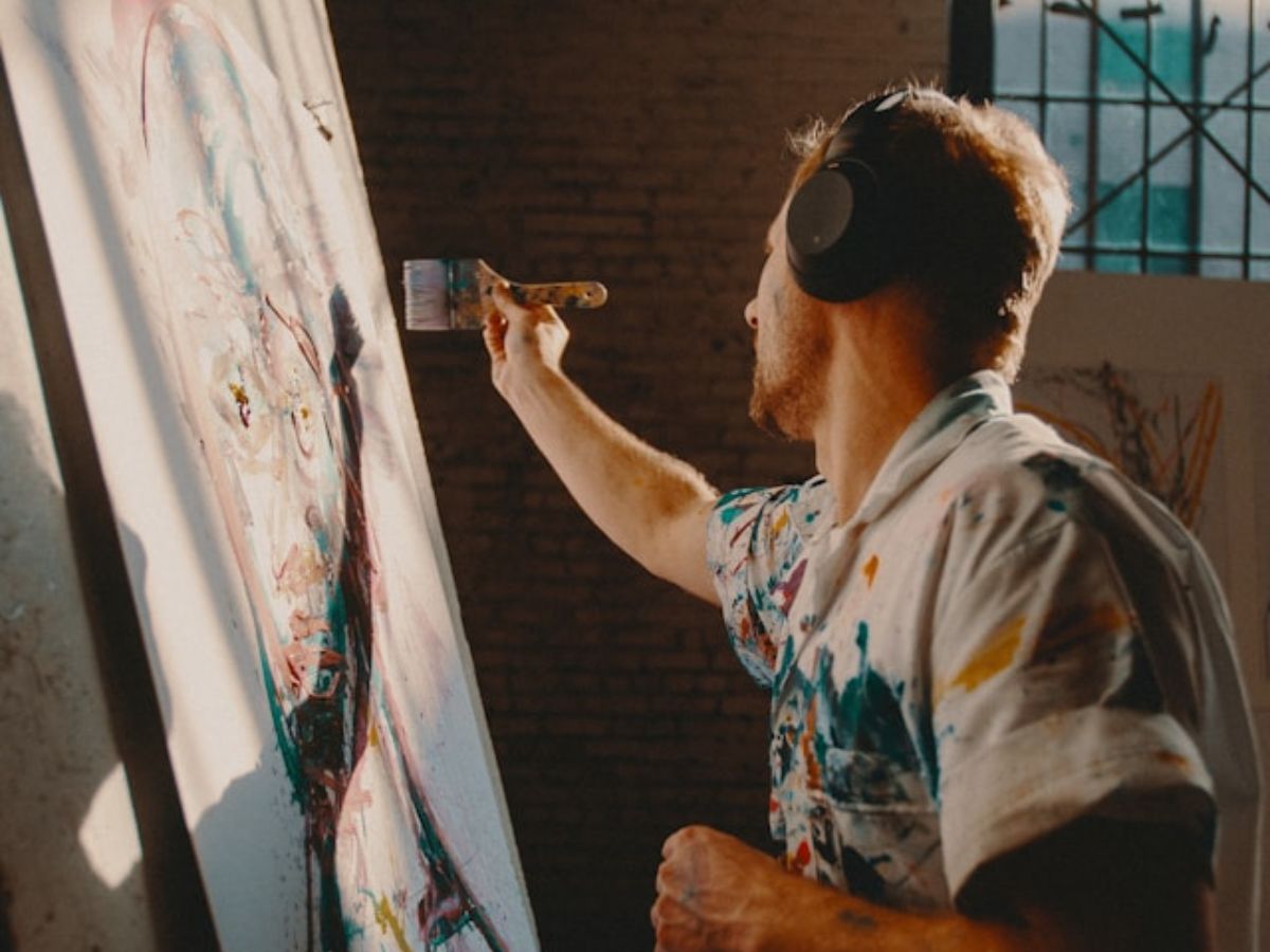 man painting on a large canvas inside a studio