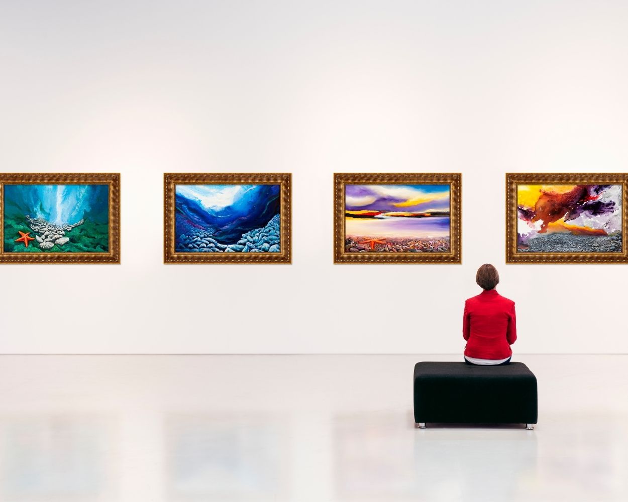 woman sitting at an art gallery while looking at canvas paintings
