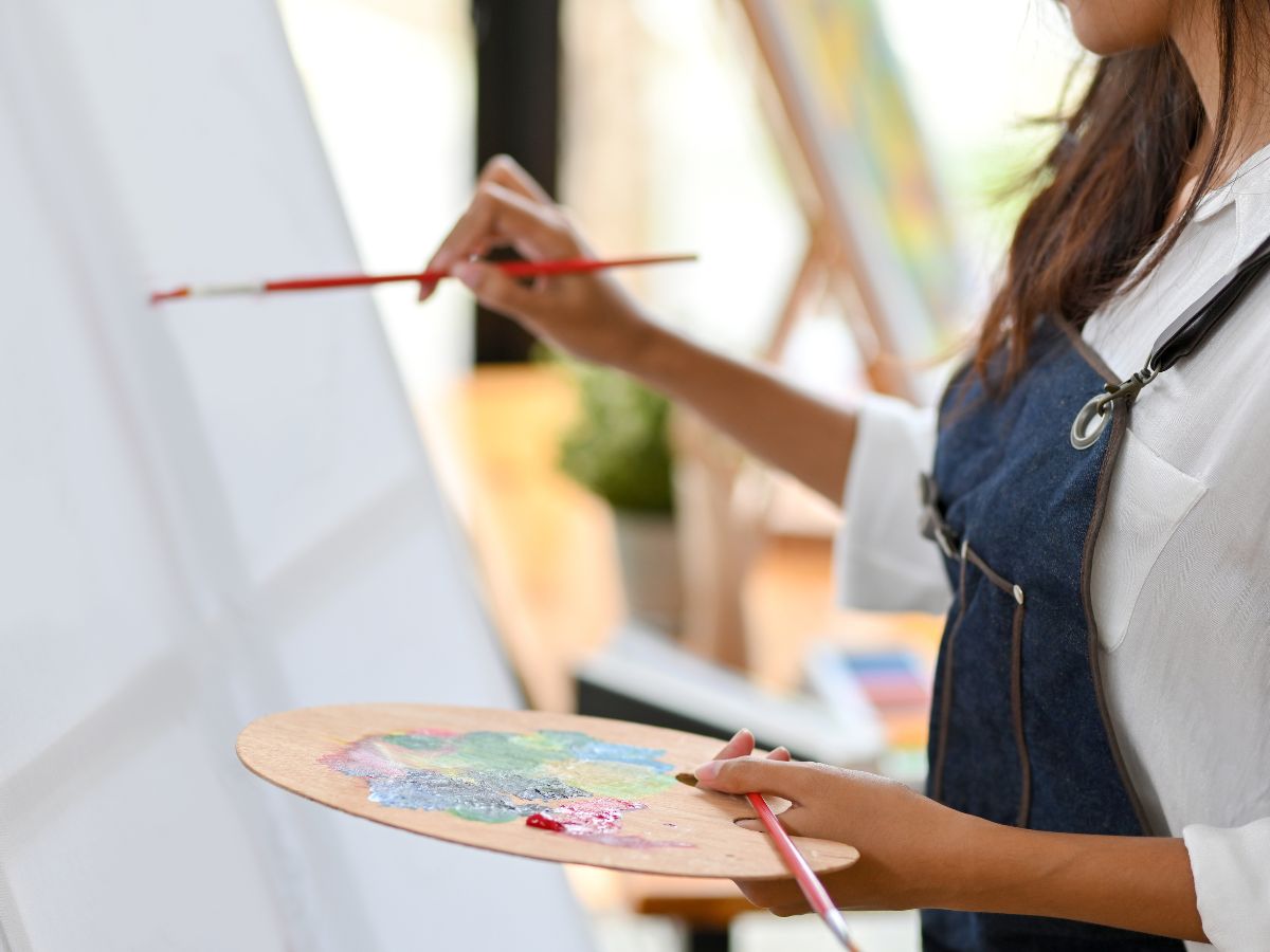 woman starts painting on blank canvas