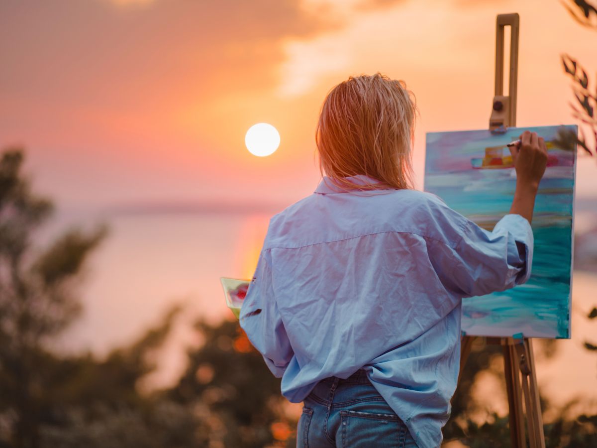 woman paints outdoors on a canvas