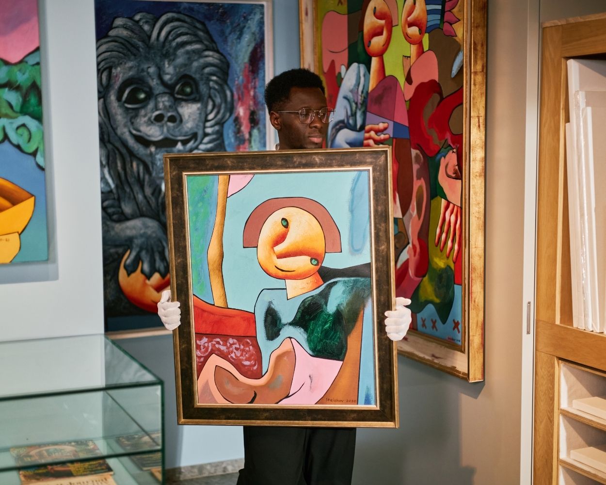 a man holding an abstract painting inside an art gallery